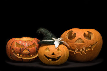 Three pumpkins with different faces for the holiday of Halloween on a black background