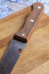 Knife with a wooden handle on a rustic kitchen cutting board