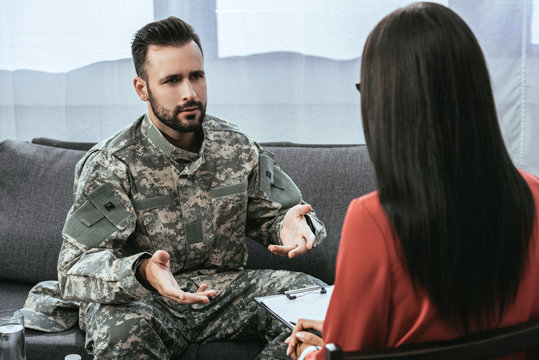 Sad Soldier With Ptsd Talking At Psychiatrist And Gesturing While Sitting On Couch During Therapy Session