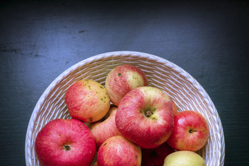 A group of red ripe apples in a basket on a background of a wooden dark table. Fresh autumn harvest. Country style. close-up