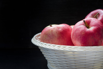 A group of red ripe apples in a basket on a background of a wooden dark table. Fresh autumn harvest. Country style. close-up