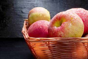 A group of red ripe apples in a basket on a background of a wooden dark table. Fresh autumn harvest. Country style. close-up