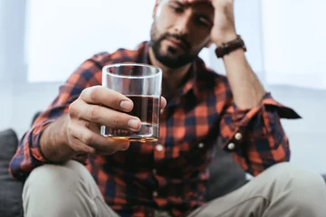Poster Im Rahmen Nahaufnahme eines depressiven jungen Mannes mit einem Glas Whisky © LIGHTFIELD STUDIOS