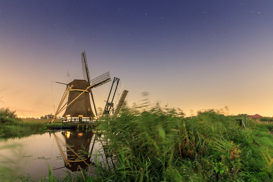 Beautiful traditional historic windmill near Baambrugge and Abcoude in the Netherlands at night with a nice reflection and lots of stars in the sky