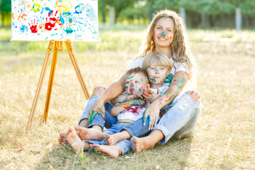 Happy family. Young pretty mother having fun with her children outdoors. Family painting