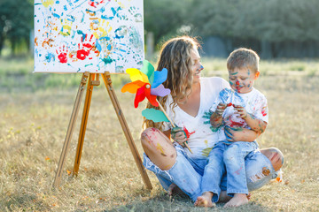 Happy family. Young pretty mother having fun with her children outdoors. Family painting
