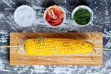 Grilled corn cob with bacon, salt and herbs.  Concept of feed corn in the restaurant