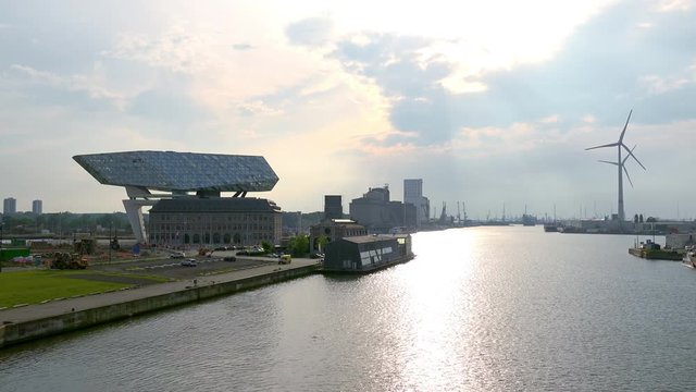 ANTWERP, BELGIUM - MAY 27, 2018: Sunset view of rotating wind turbines and Antwerp Port House. Futuristic postmodern architecture created by Zaha Hadid. Impressive building of seaport authority.