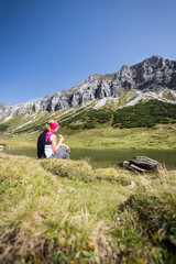 Junge blonde Frau rastet am Ufer eines Bergsees, Österreich