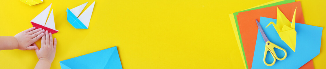 Web banner, origami kids.  Color cranes of origami from paper on a yellow background