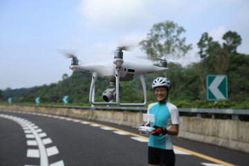 Woman control the white drone flying above highway