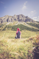 Junge blonde Frau rastet am Ufer eines Bergsees, Österreich