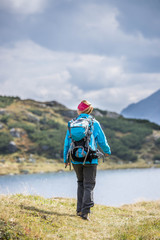 Junge Frau mit Rucksack wandert in den Alpen, Alpensee