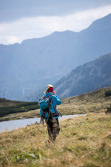 Fototapeta na wymiar Junge Frau mit Rucksack wandert in den Alpen, Alpensee