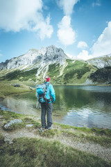 Junge blonde Frau betrachtet die Landschaft in den Berge, Bergsee und Gipfel