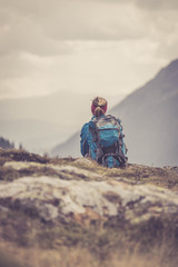 Junge blonde Frau sitzend in den Bergen, Blick in die Ferne, Abenteuer