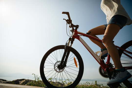 Hands free cycling woman riding mountain mike on sunrise seaside