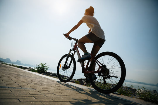 Cycling woman riding mountain mike on sunrise seaside