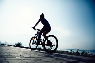 Fototapeta na wymiar Cycling woman riding mountain mike on sunrise seaside