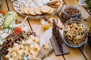 Close-up cheese bar of several kinds of cheese, snacks, honey, nuts decorated on wooden table at the wedding party. Concept of food.