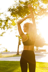 Beautiful young blonde sports woman in park outdoors make stretching exercises.