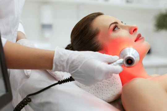 Facial Beauty Treatment. Woman Doing Red Led Light Therapy 