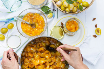 Plum jam in the pot and woman puts it to jars, food and healthy eating concept