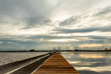 Naklejka premium Sunset light reflects from the surface of the water and the wooden bridge.