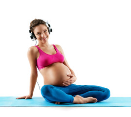 Fototapeta na wymiar Pregnant woman with headphones touching her belly and relaxing isolated on white background. Concept of healthy life