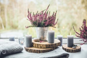 Getting ready for autumn. Cozy autumn set. Gray candles, flame wooden boards, common pink heather flower in zinc bucket pot. Cozy Nordic Scandinavian style living space concept.