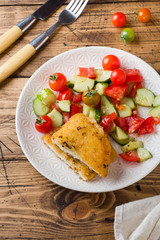 Chicken cutlet and cucumber salad with tomatoes on a wooden table