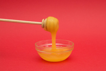 candied honey on spoon, spindle for honey on red background with copy space