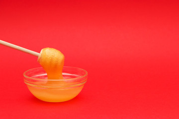 candied honey on spoon, spindle for honey on red background with copy space