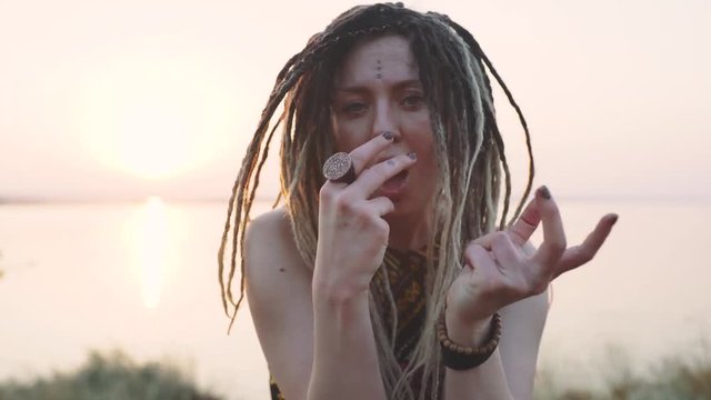 attractive hippie woman with dreadlocks at sunset having good time and dance outdoors