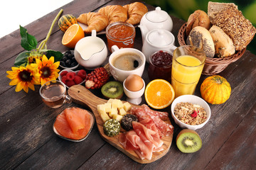 breakfast on table with bread buns, croissants, coffe and juice.