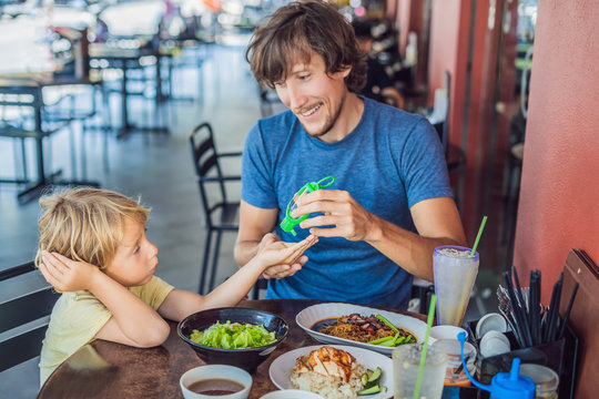 Father and son using wash hand sanitizer gel before eating in a cafe