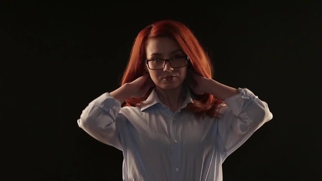 a beautiful girl with red hair in a white shirt posing on a black background in front of the camera. the model advertises glasses, lenses or services to restore vision
