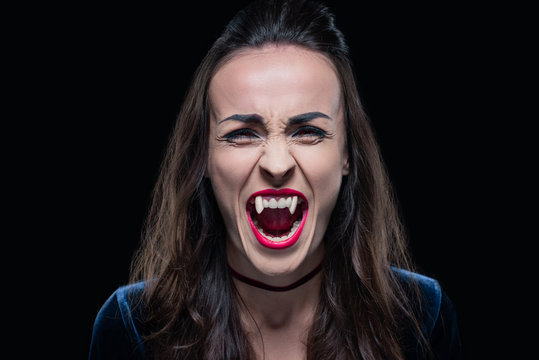 gothic woman showing vampire teeth isolated on black