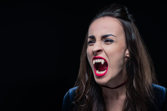 dreadful woman showing vampire teeth isolated on black