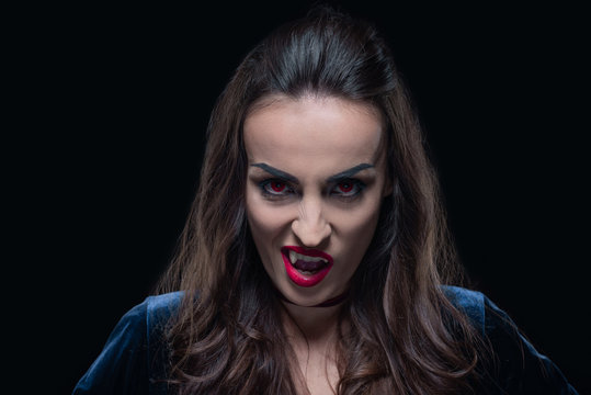 horror woman showing vampire fangs isolated on black