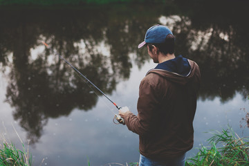 Young fisherman is fishing in river with spinning