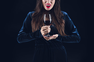 cropped view of vampire holding wineglass with blood isolated on black