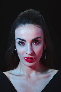 sexy vampire woman with red eyes looking at camera isolated on black