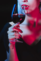 cropped view of vampire drinking blood from wineglass isolated on black