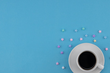 A cup of coffee decorate with pastel stars on blue background with copy space