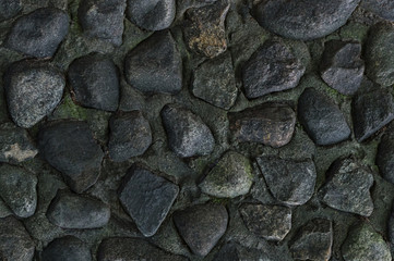 stones dark black gray cement wall part of an old river mouth dried up close-up background design base