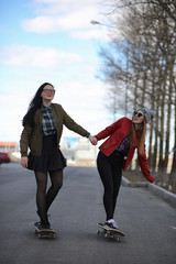 Obraz premium A young hipster girl is riding a skateboard. Girls girlfriends f