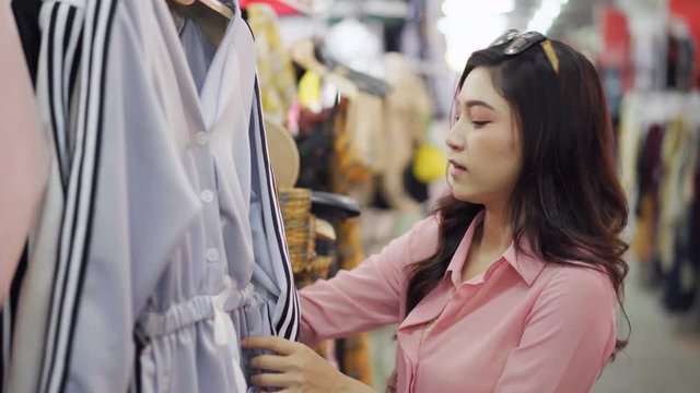 woman choosing and buying clothes in shopping store