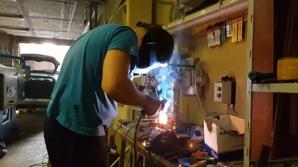 Experienced technician heating metal with welding equipment, repairment process
