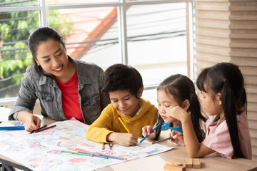 Asian Teacher teaching Art and coloring with little kids.